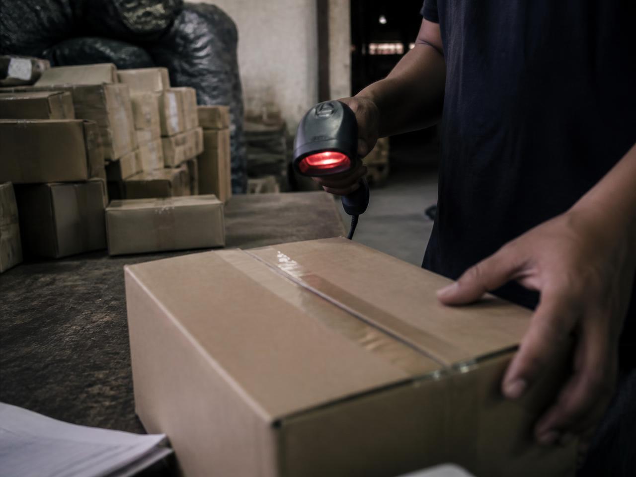 Worker scanning and packing boxes inside a warehouse